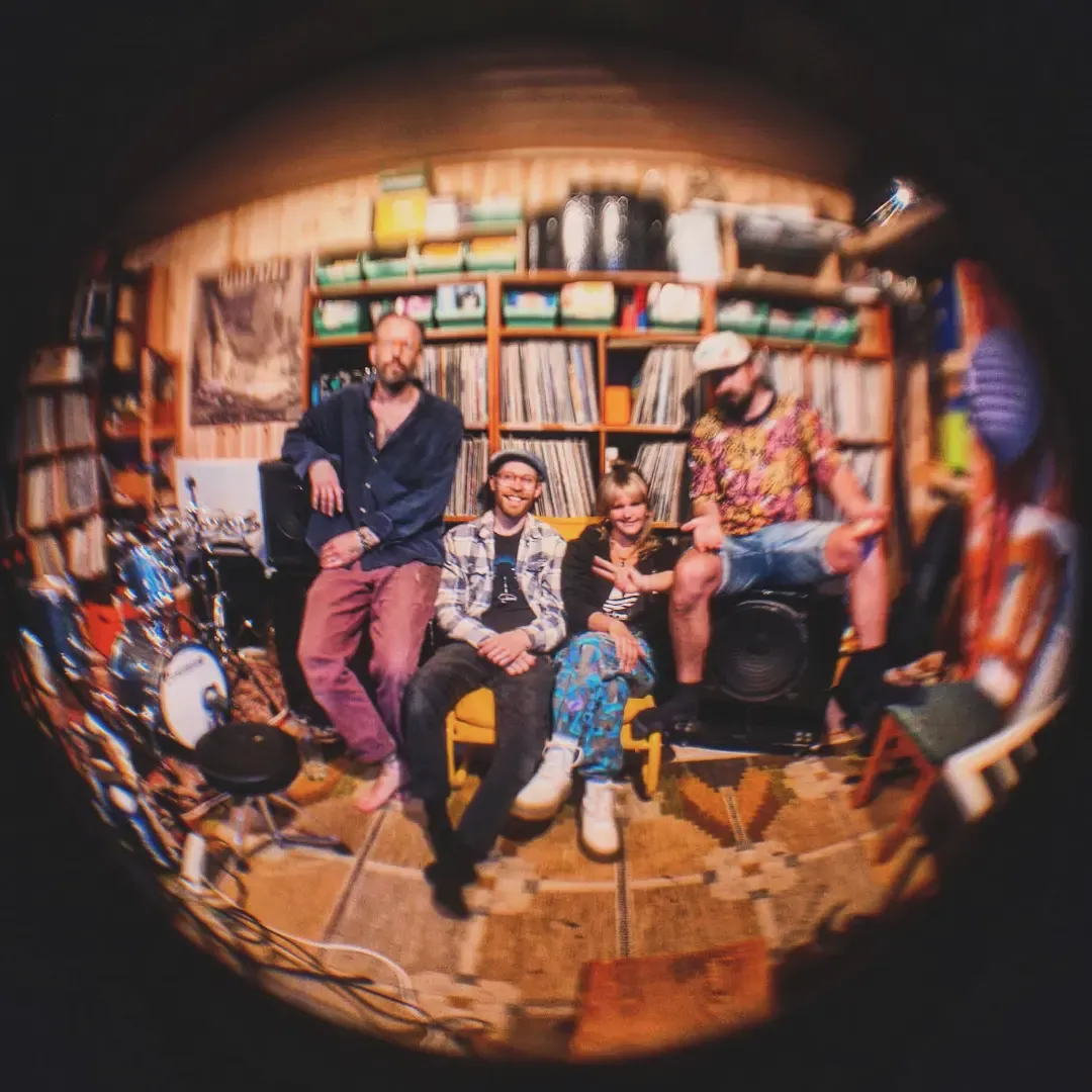 Bandet i ett rum fullt av vinylskivor, fotograferat med fisheye.