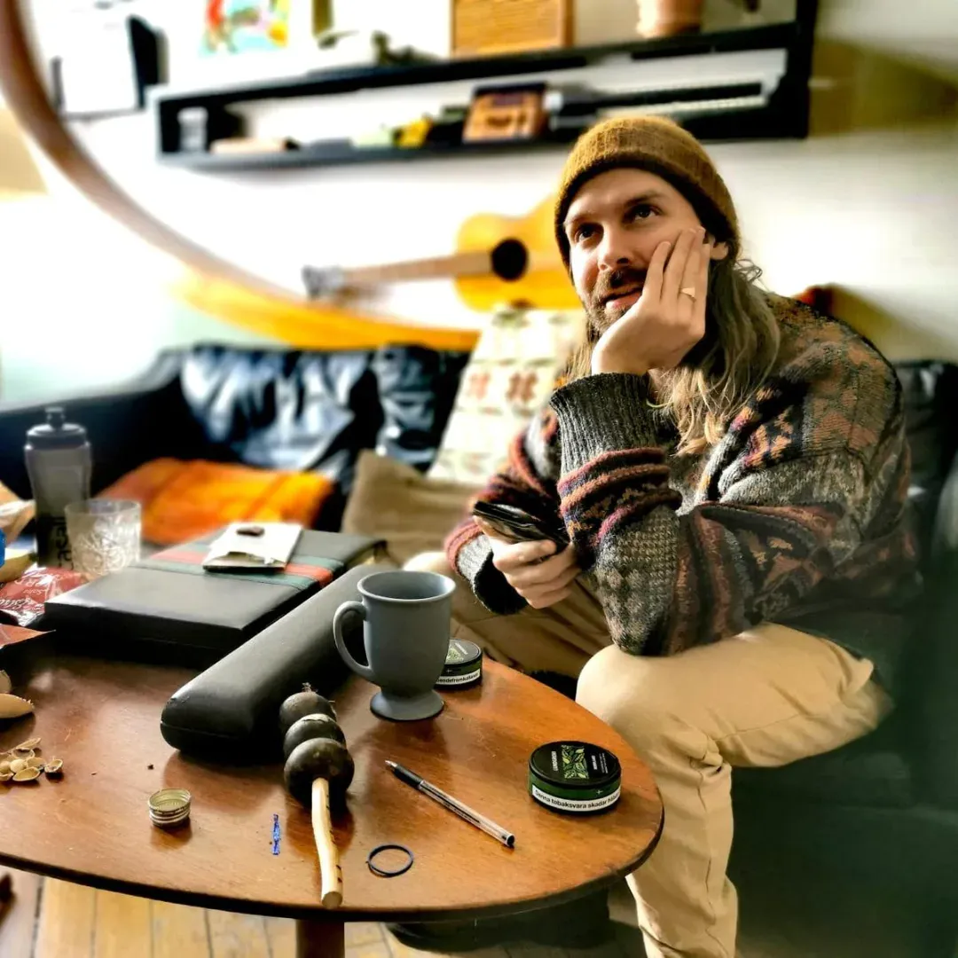 Bandets saxofonist i stickad mössa vilar hakan i handen.